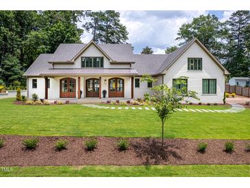 Inviting exterior of a bright, white home with a manicured lawn and charming walkway to the front door at 4412 Pamlico Dr, Raleigh, NC 27609