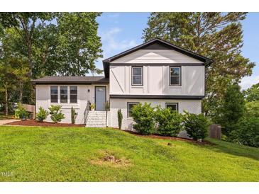 Charming two-story white brick home with black trim, well-manicured lawn, and lush landscaping at 5400 Kaplan Dr, Raleigh, NC 27606