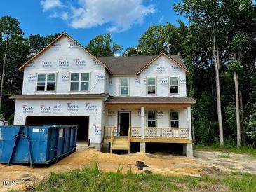 Two-story home featuring large windows and a covered porch, currently under construction at 683 Little River Dr, Zebulon, NC 27597