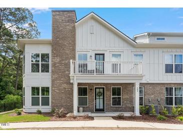 Charming two-story exterior showing a combination of brick and white siding with a quaint balcony and well-maintained landscaping at 11548 Helmond Way # 104, Raleigh, NC 27617