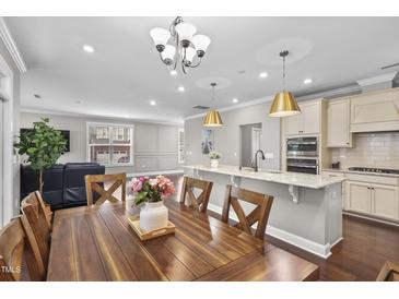 Bright kitchen with stainless appliances, granite counters, hardwood floors and a large kitchen island at 1313 Littlehills Dr, Apex, NC 27523