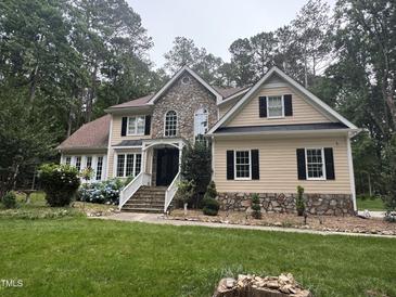 Charming two-story home with stone accents, a well-manicured lawn, and beautiful landscaping at 6225 Acorn Ridge Trl, Hillsborough, NC 27278
