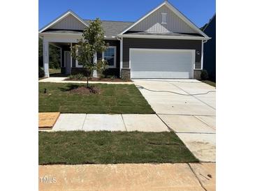 Charming home featuring a covered porch, two-car garage, and freshly laid sod at 144 N Keatts Winner Ct, Wilson's Mills, NC 27520