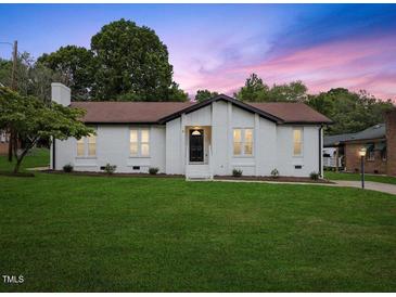 Charming home with a brick exterior, well-manicured lawn, and a picturesque sunset backdrop at 1709 Hawthorne Lane Ln, Burlington, NC 27215