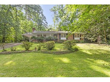 Charming brick home featuring a well-manicured lawn and mature trees, offering a serene and inviting curb appeal at 2406 Oxford Rd, Raleigh, NC 27608