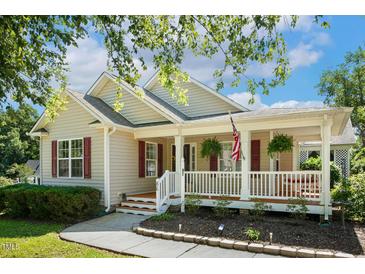 Charming single Gathering home showcasing a cozy porch with an American flag and lovely landscaping at 86 Basswood Cir, Willow Springs, NC 27592