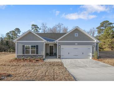 Charming one-story home with gray siding, a two-car garage, and a well-manicured lawn at 294 Pretty Run Branch Ln, Wendell, NC 27591