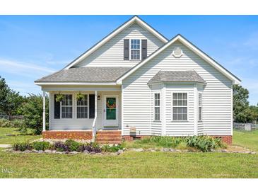 Charming home featuring white siding, a cozy front porch, and manicured landscaping at 3831 Abattoir Rd, Angier, NC 27501