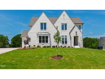 Stunning two-story home with a white brick exterior, manicured lawn, and professional landscaping at 808 Shiloh Hills Dr, Fuquay Varina, NC 27526