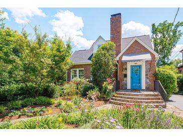Charming brick home with a beautiful, lush front garden and a vibrant blue front door at 1007 W Markham Ave, Durham, NC 27701