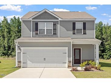Charming two-story home with a two-car garage, gray siding, and a well-manicured lawn at 154 Taverners Ln, Angier, NC 27501