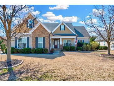 Charming two-story home with a mix of stone and siding, a well-maintained lawn and mature trees at 1624 Struble Cir, Willow Springs, NC 27592