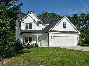 Charming two-story home boasts a manicured lawn, attached two car garage, and cozy front porch perfect for relaxing at 221 Stella Way, Cameron, NC 28326