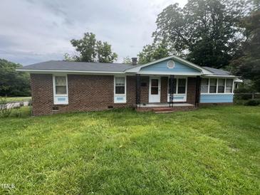 Charming brick home featuring a covered front porch, updated trim, and freshly mowed lawn at 503 Adams St, Henderson, NC 27536