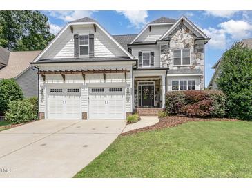 Charming two-story home featuring a stone facade, a three-car garage, and a well-manicured lawn at 5629 Clearsprings Dr, Wake Forest, NC 27587