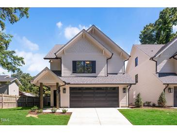 Charming two-story home featuring a gray roof, a two-car garage, and a well-manicured lawn at 703 E Markham Ave, Durham, NC 27701