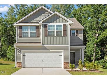 Charming two-story home with gray siding, stone accents, and a two-car garage at 94 Taverners Ln, Angier, NC 27501