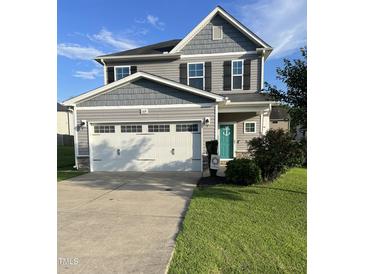 Charming two-story home featuring a two-car garage, manicured lawn, and inviting turquoise front door at 109 E Webber Lane Ln, Clayton, NC 27527