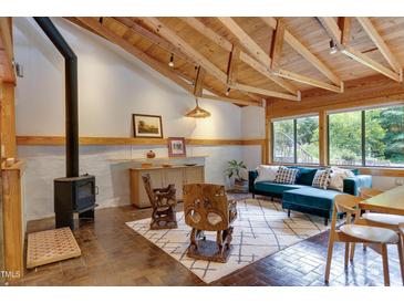 Inviting living room featuring a beamed ceiling, wood burning fireplace, and large picture windows at 1320 Shepherd St, Durham, NC 27707