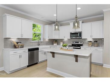 Bright kitchen features white cabinets, stainless steel appliances, and a center island perfect for meal prep and entertaining at 141 Alden Way, Angier, NC 27501