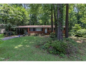 Charming brick home featuring a well-maintained lawn and mature trees, providing a serene and inviting curb appeal at 1500 Lakeside Dr, Garner, NC 27529