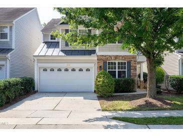 Charming home featuring a stone facade, a two-car garage, and a beautifully landscaped front yard with mature trees at 238 Royal Tower Way, Cary, NC 27513