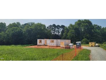 Framed home under construction showcasing the initial structure and design in a grassy lot surrounded by trees at 5545 Silk Hope Gum Springs Rd, Siler City, NC 27344