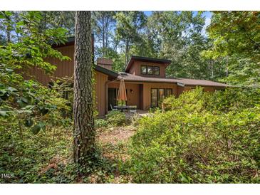 Charming home featuring a wood exterior surrounded by lush greenery and mature trees at 6700 Falconbridge Rd, Chapel Hill, NC 27517