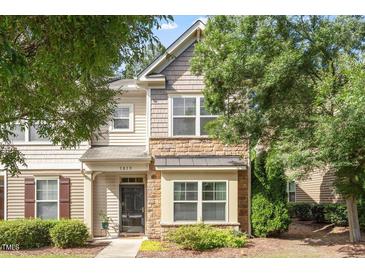 Charming townhome featuring a stone and shake facade, a black front door, and beautifully landscaped grounds at 7879 Allscott Way, Raleigh, NC 27612