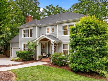 Charming gray two-story home with a welcoming front porch and manicured landscaping surrounded by mature trees at 105 Jolyn Pl, Chapel Hill, NC 27517