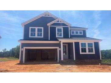 Two-story home features a two-car garage, blue siding and white trim, enhancing its curb appeal at 216 Sprenger St, Garner, NC 27529