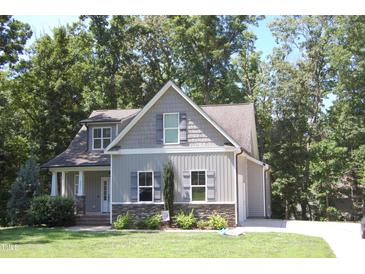 Charming home with gray siding, stone accents, and lush landscaping in a serene, tree-lined setting at 2471 Golden Forest Dr, Franklinton, NC 27525