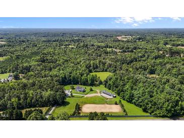Expansive aerial view of horse property featuring a home, stable, and riding arena surrounded by lush greenery and wooded areas at 3511 Corbett Rd, Mebane, NC 27302