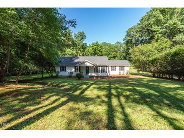 Charming single-story home with a lush green front yard and mature trees offering plenty of shade on a sunny day at 514 Lipscomb Grove Church Rd, Hillsborough, NC 27278