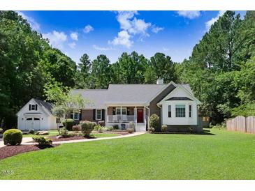 Charming home with a well-manicured lawn and inviting curb appeal, framed by mature trees and a detached garage at 10031 Old Middlesex Rd, Middlesex, NC 27557