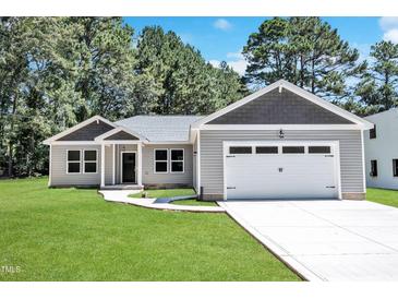Charming one-story home with a manicured lawn and attached two car garage at 125 Davis St, Louisburg, NC 27549