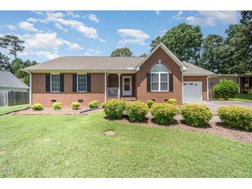 Charming brick home featuring manicured landscaping, a manicured lawn, and an attached garage in a suburban setting at 1822 Atterbury Ln, Durham, NC 27712