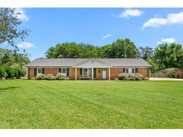 Charming brick home with a manicured lawn, lush landscaping, and a welcoming front porch at 2119 Northcrest Dr, Elon, NC 27244