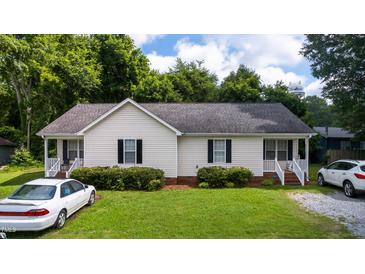 Charming single-story home with well-maintained lawn and landscaping under a partly cloudy sky at 308 E Gilbreath St, Graham, NC 27253