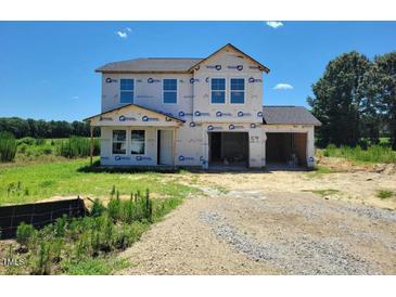 New two-story home showcasing a two-car garage under construction with an unfinished lawn and pleasant tree line at 3895 Josiah Ct, Nashville, NC 27856