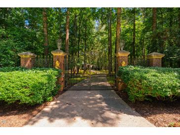 Ornate brick and iron gate leads to a private, tree-lined driveway and estate at 8200 Bromley Rd, Hillsborough, NC 27278