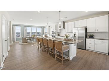 Bright, open kitchen features a large island with seating, stainless steel appliances, and modern white cabinetry at 1242 Coach Station Alley # 201, Raleigh, NC 27601