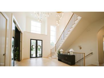 Bright foyer with high ceilings, statement lighting, staircase, and black double doors at 1620 Hunting Ridge Rd, Raleigh, NC 27615