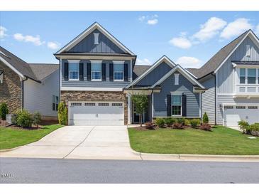 Charming two-story home with a stone accent, a two-car garage and manicured landscaping at 705 Churton Pl, Cary, NC 27518