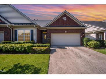Charming brick home featuring a two-car garage, manicured lawn, and beautiful landscaping at 8007 Crookneck Dr, Angier, NC 27501