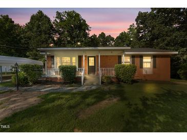 Charming brick home featuring a covered front porch with a white railing and well-maintained landscaping at 904 Lanier Farm Rd, Sanford, NC 27330