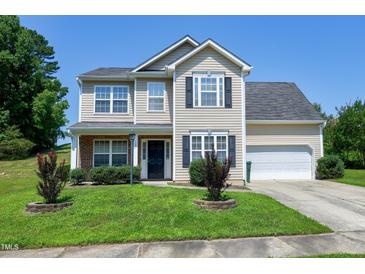 Charming two-story home with a well-maintained lawn, attached garage, and inviting curb appeal on a sunny day at 103 Bermuda Green Dr, Durham, NC 27703