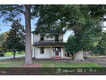 Two-story house with a covered front porch and mature trees in the front yard at 12670 School House Rd, Middlesex, NC 27557