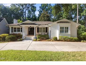 Charming one-story home featuring a white brick exterior, manicured landscaping, and a welcoming covered front porch at 227 W Drewry Ln, Raleigh, NC 27609