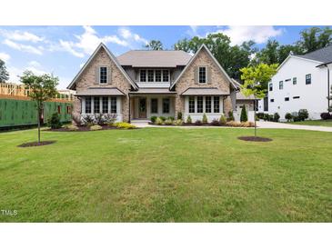 Charming two-story home featuring stone accents, multi-pane windows, manicured landscaping, and a lush green lawn at 1212 Gunnison Pl, Raleigh, NC 27609